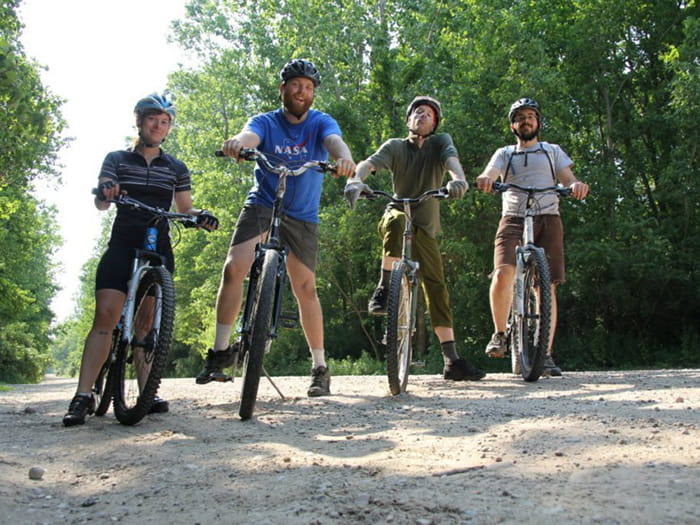 four mountain bikers posing on dirt road