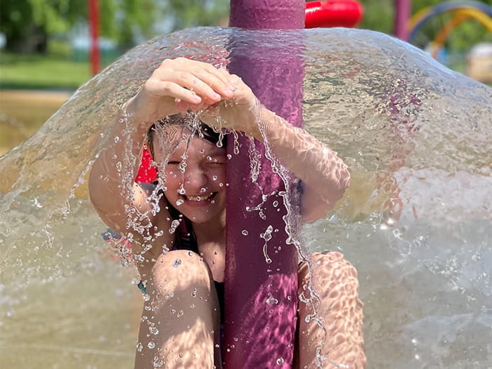 child sitting under water spray feature