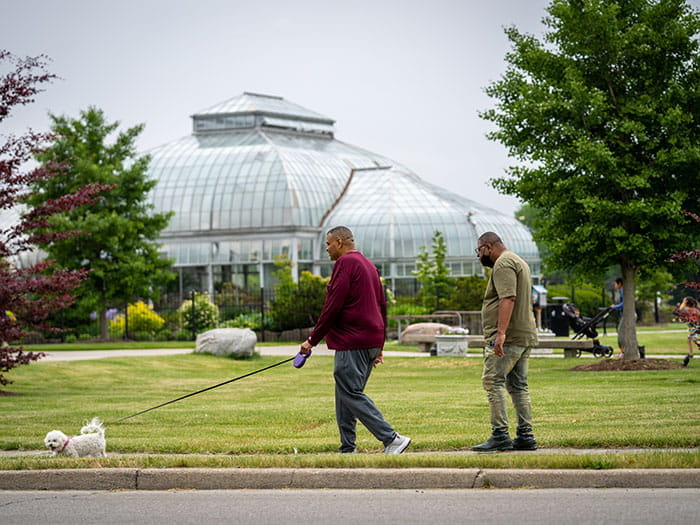 two men walking dog in front conservatory dome