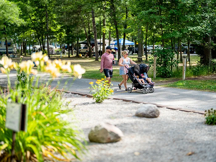 parents pushing stroller on paved path in campground