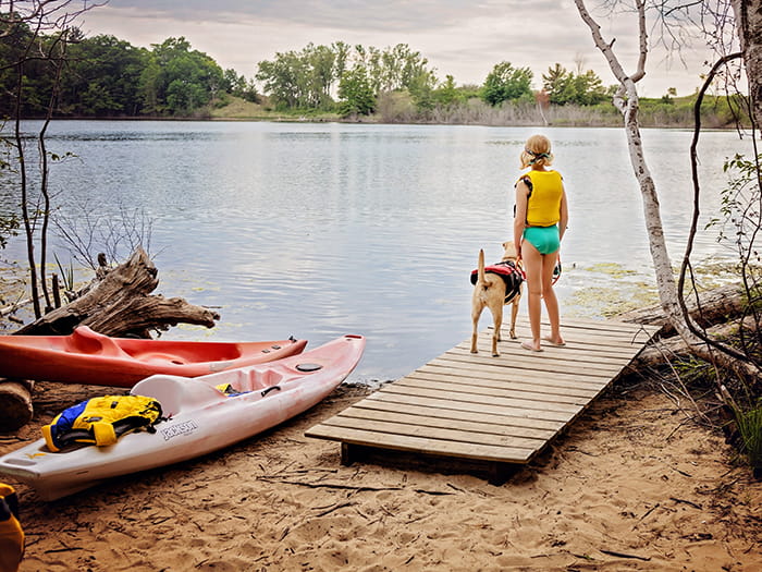 child stadning with leashed dog on kayak launch photo by Morgan Aislyn Liskey