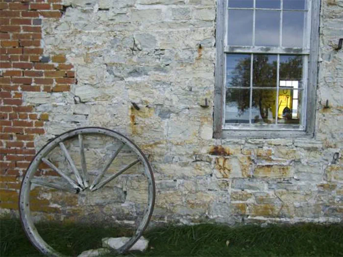 historic building with wooden wheel set against brick wall