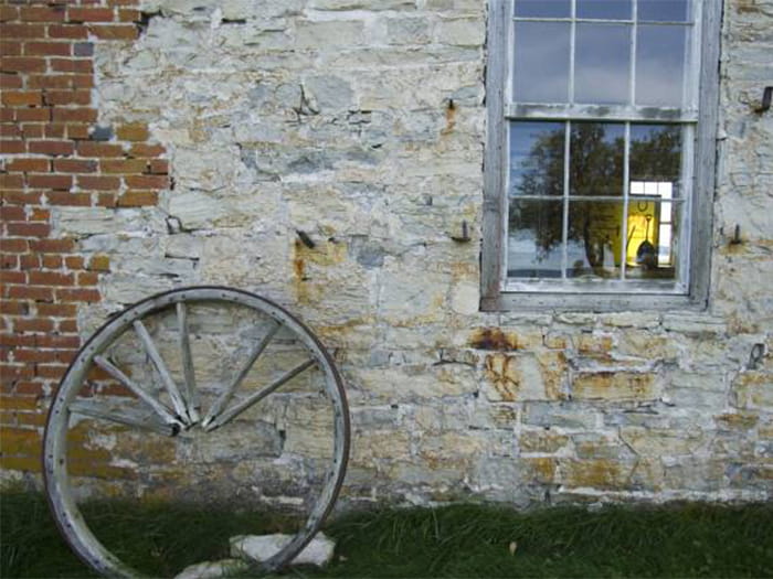 historic building with wooden wheel set against brick wall