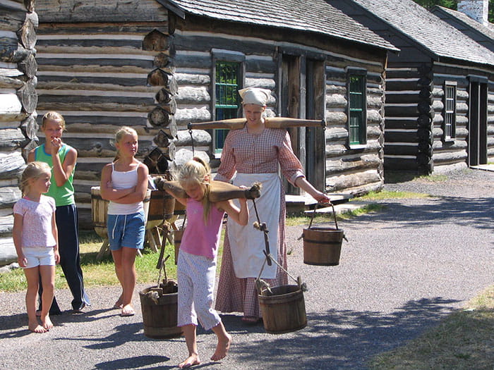 kids holding water pails in historic village