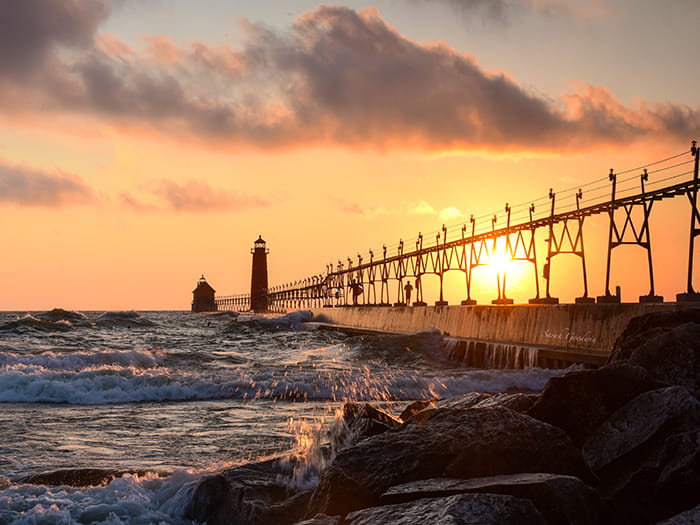 sun behind pier and lighthouses