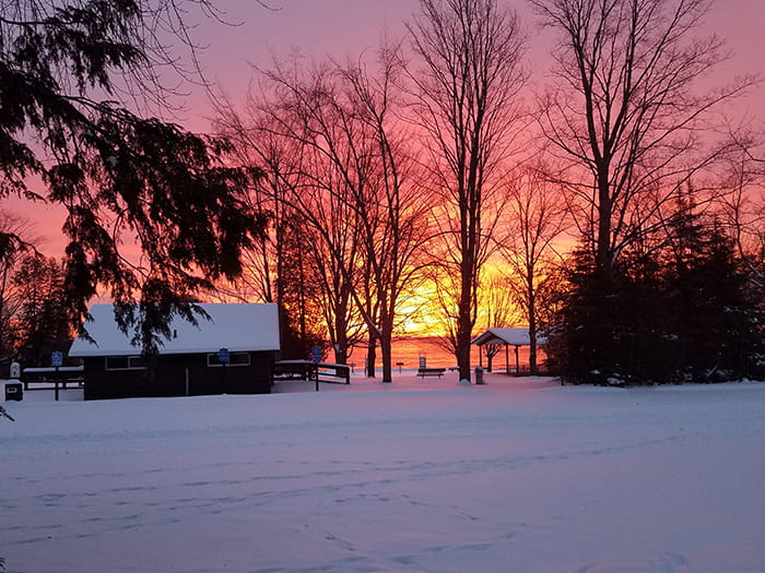 snow covered ground with day use buildings and pink horizon