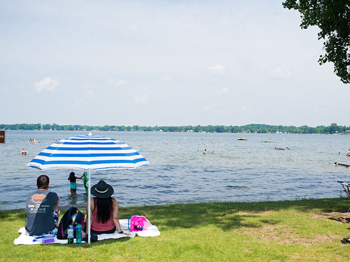family sitting on shore with umbrella