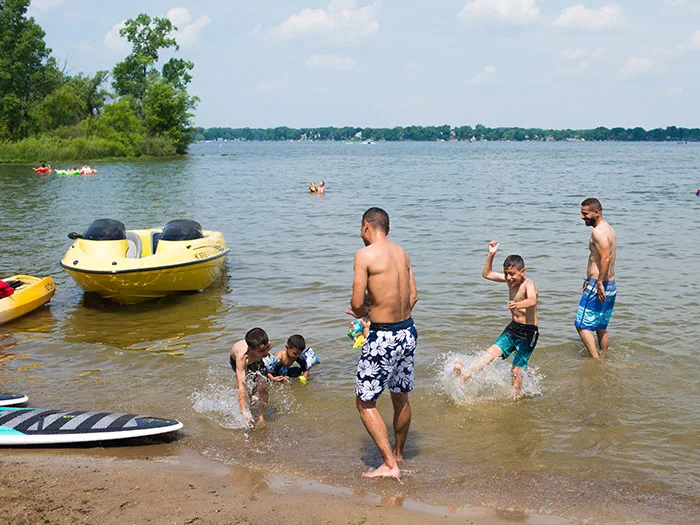 people splashing in water with boats parked nearby