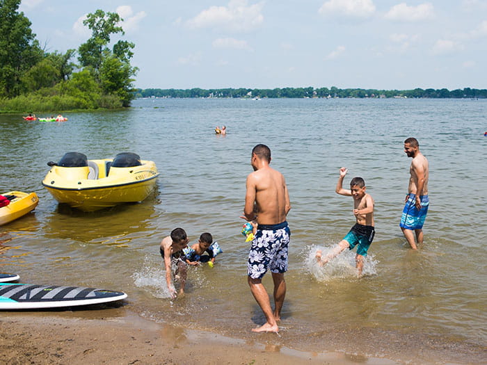 people splashing in water with boats parked nearby