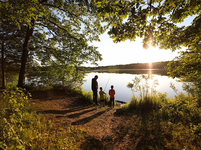 family standing on shoreline fishing