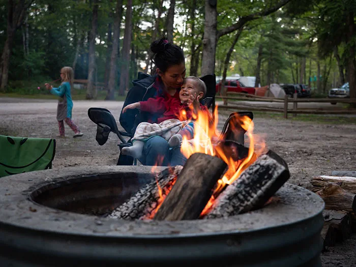 mother and child snuggling next to the campfire