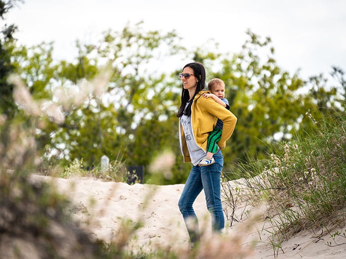 mother holding child on her back on sandy dune