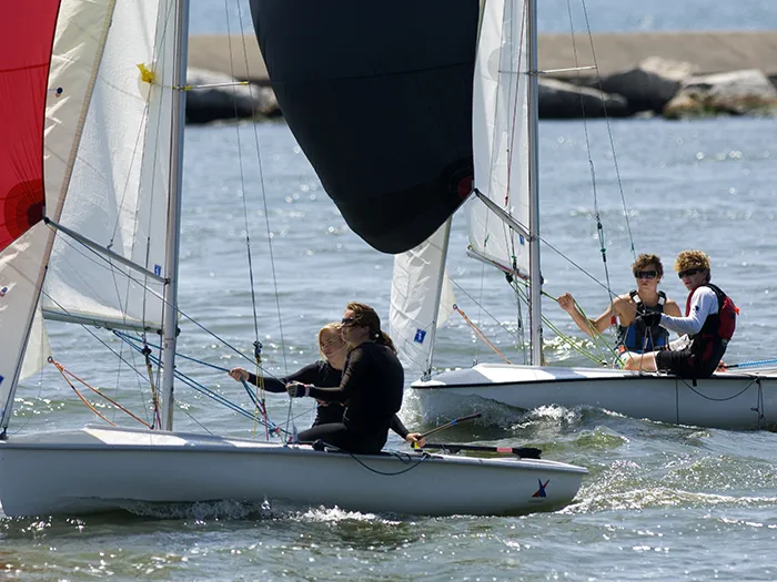 two sailboats in channel with breakwall in background