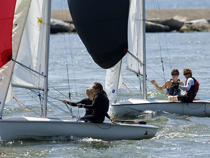 two sailboats in channel with breakwall in background