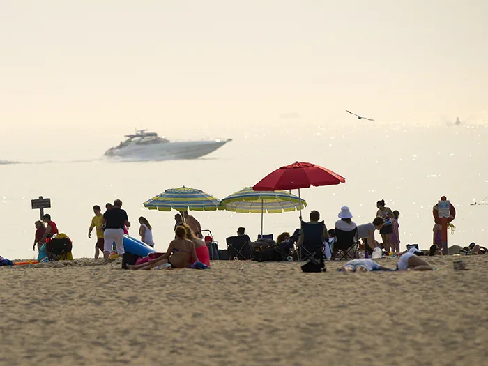 boat parallel to lakeshore with beachgoers