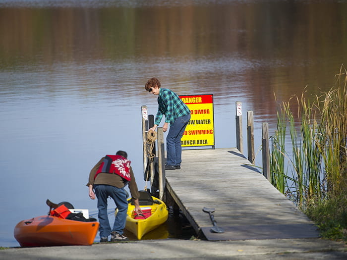 couple launching kayaks from boat launch