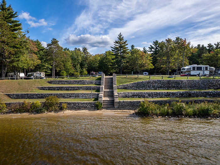 terraced stone wall above lake with campers