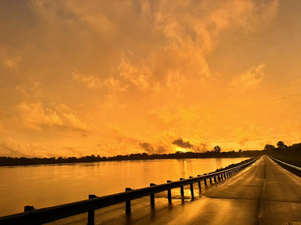 orange-lit sky over road and lake