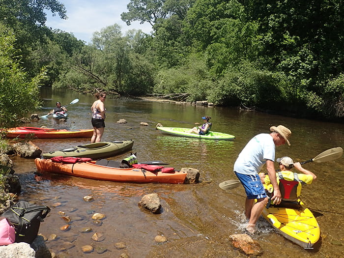 paddlers getting in colorful kayaks in river