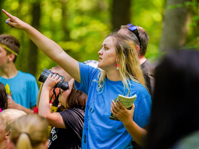 naturalist pointing up with families behind