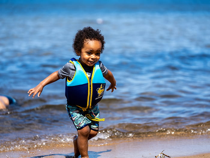 Kid running out of water with life jacket
