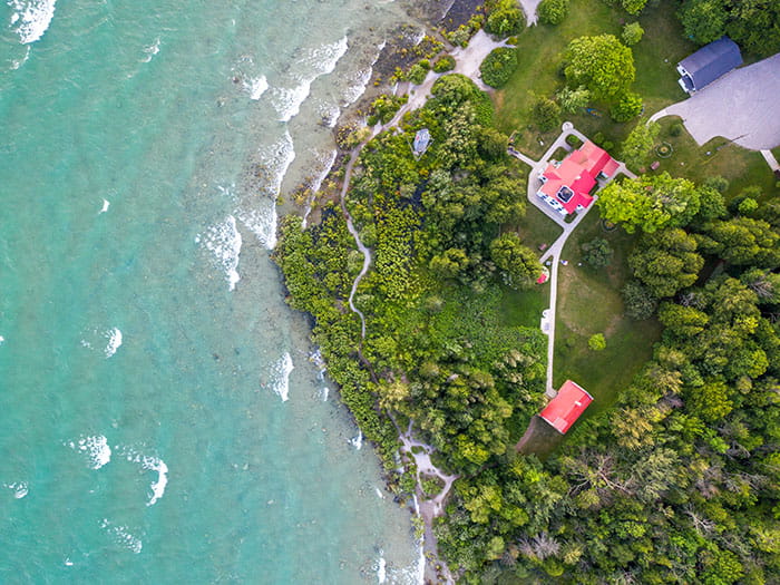 birds eye view of blue water lighthouse and land