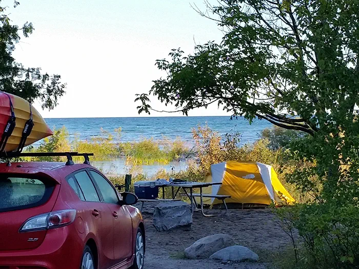 car and tent in campsite along lake
