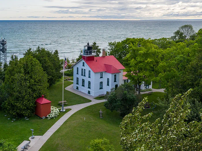 lighthouse builidng with surrounding trees and lake