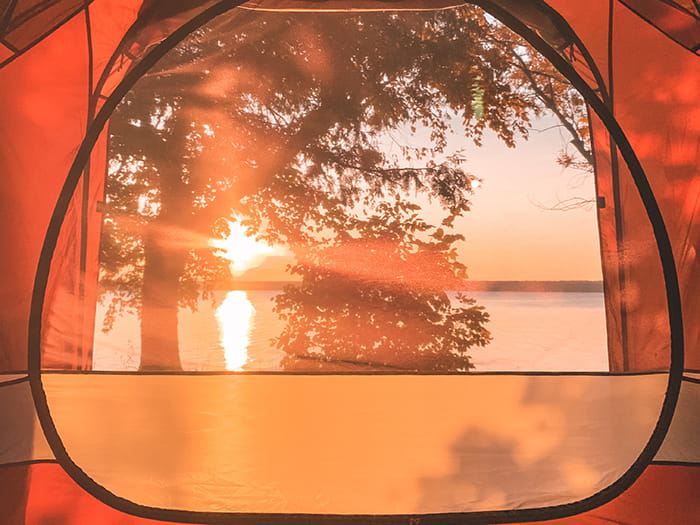 view of lake with sun setting through tent window