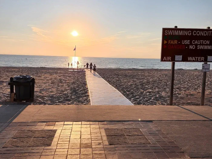 walkway to water with swimming condition signage