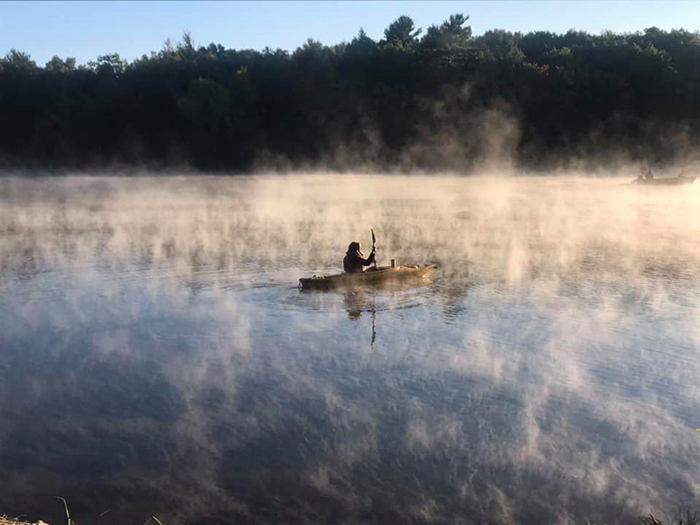 kayaker paddling in mist on lake