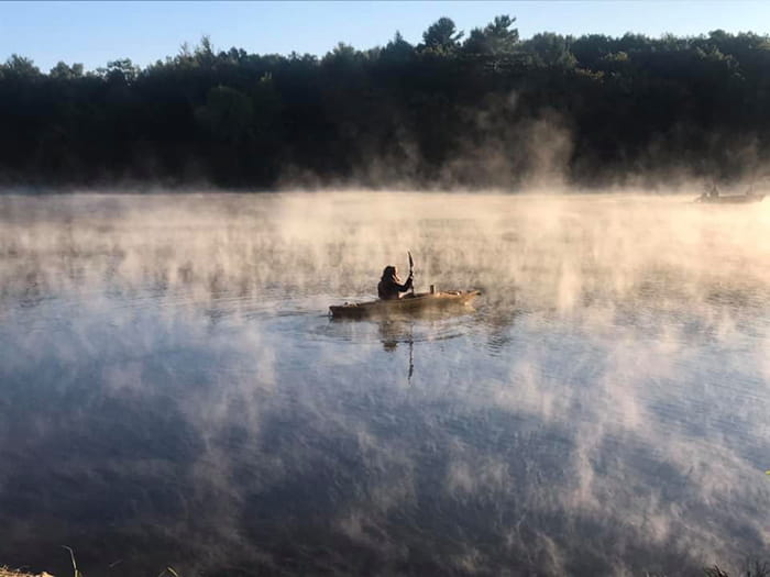 kayaker paddling in mist on lake