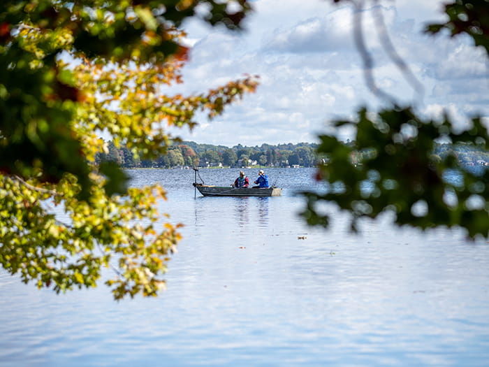 two anglers in fishing boat framed by trees