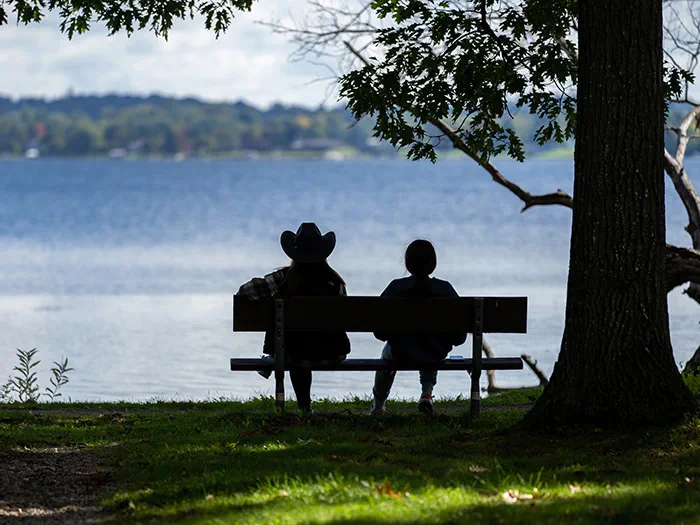 two people sitting on bench looking at lake