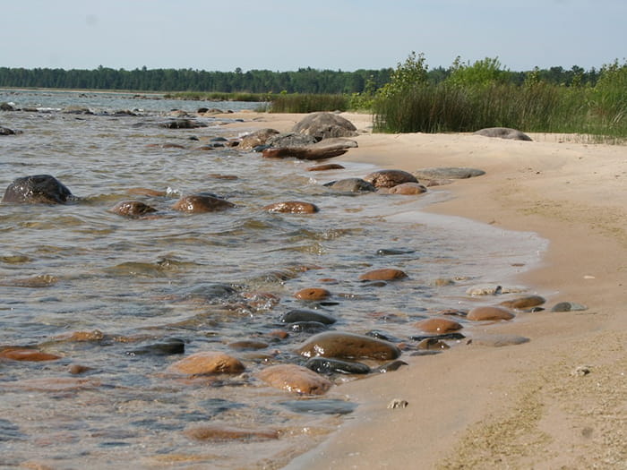 sandy shoreline with water over rocks