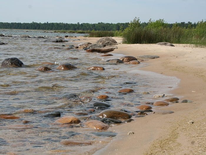 sandy shoreline with water over rocks