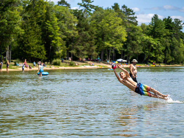 kid jumping to catch ball in water