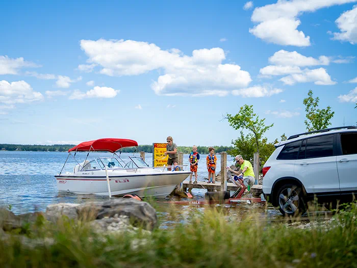 family loading onto boat from boat ramp with car backed in