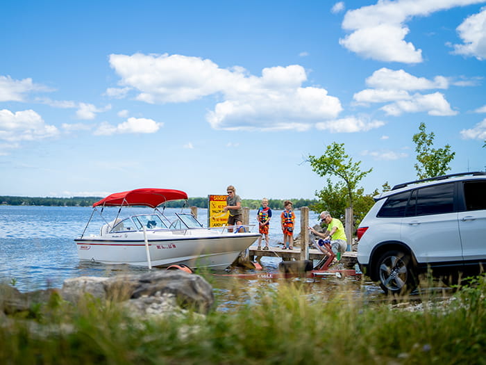 family loading onto boat from boat ramp with car backed in