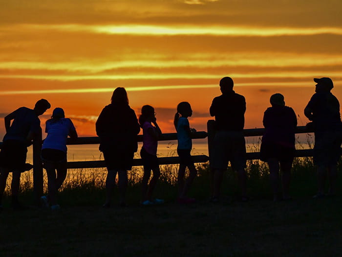 silhouettes against Lake Michigan sunet along fence