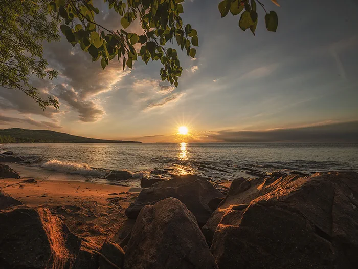 Sun setting over water with rocks