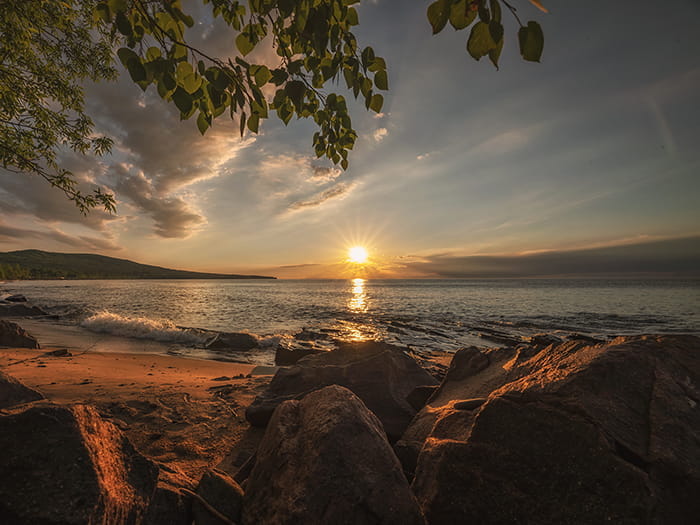 Sun setting over water with rocks