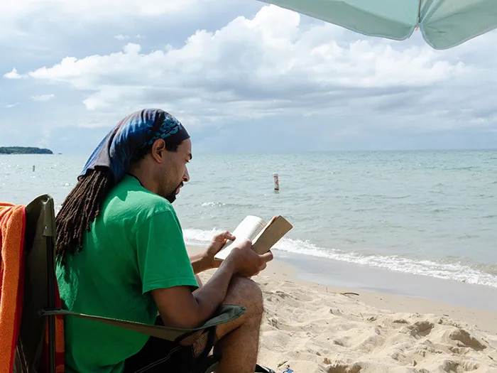 man reading on sandy shoreline