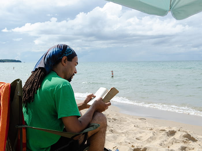 man reading on sandy shoreline