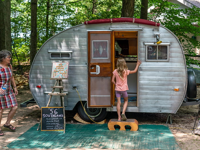 young girl stepping into vintage tin camper
