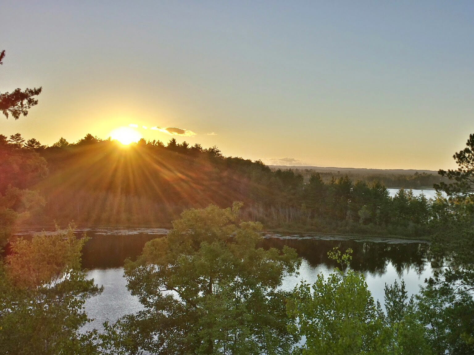 sunset over tree line and water