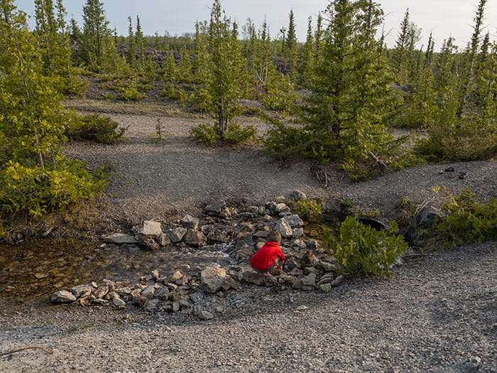 A small child in a red shirt searching through a pile of rocks