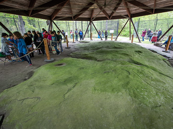 kids standing around petroglyphs under roofed enclosure