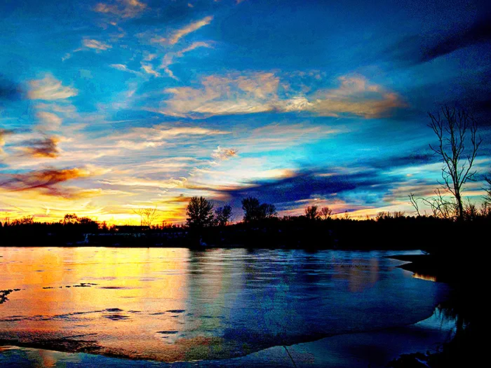 vibrant blue and yellow sky reflected in lake