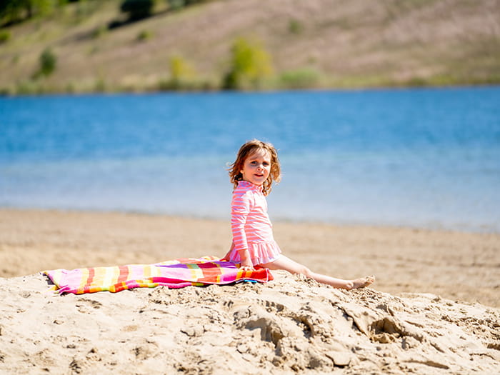 young girl sitting on sandy beach